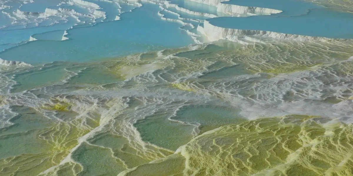 Aerial view of layered coastal rock formations with turquoise water, illustrating a natural landscape.