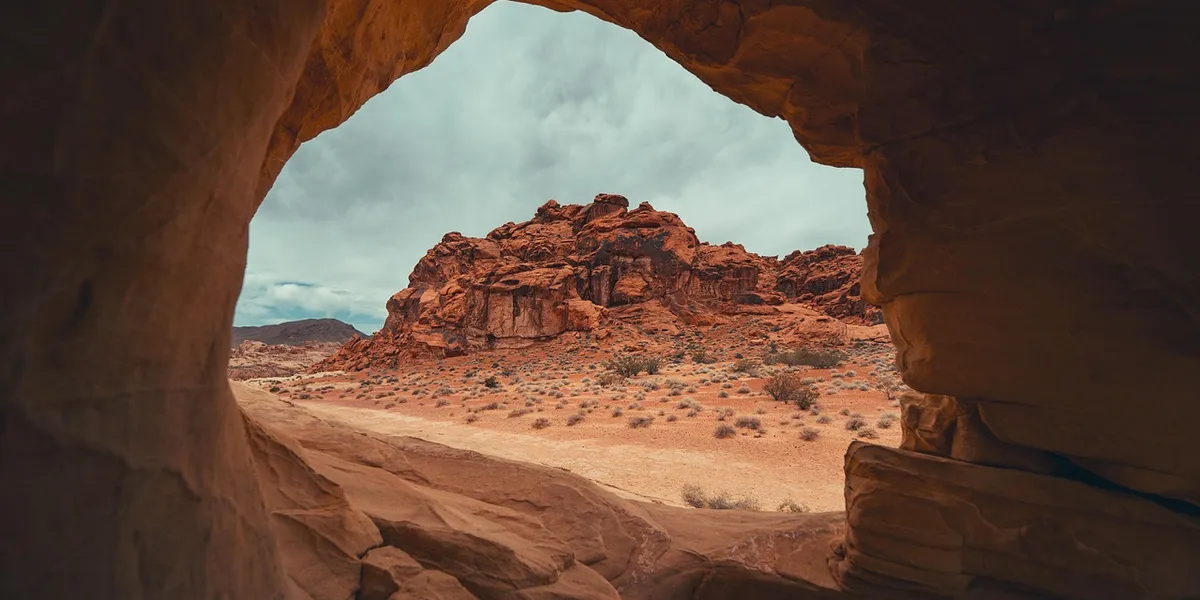 Red desert rock formations in a canyon under a cloudy sky