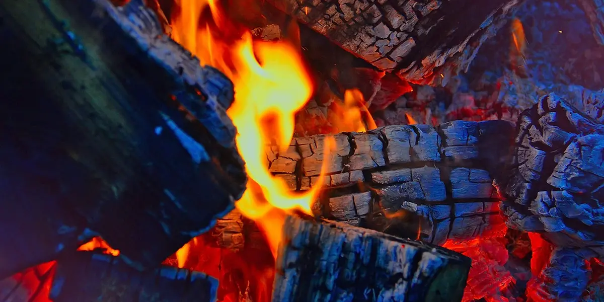 Close-up of bright orange flames and glowing embers, illustrating radiant heat.