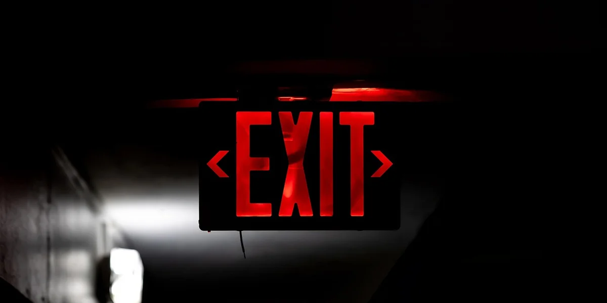 Red illuminated EXIT sign in a dark hallway