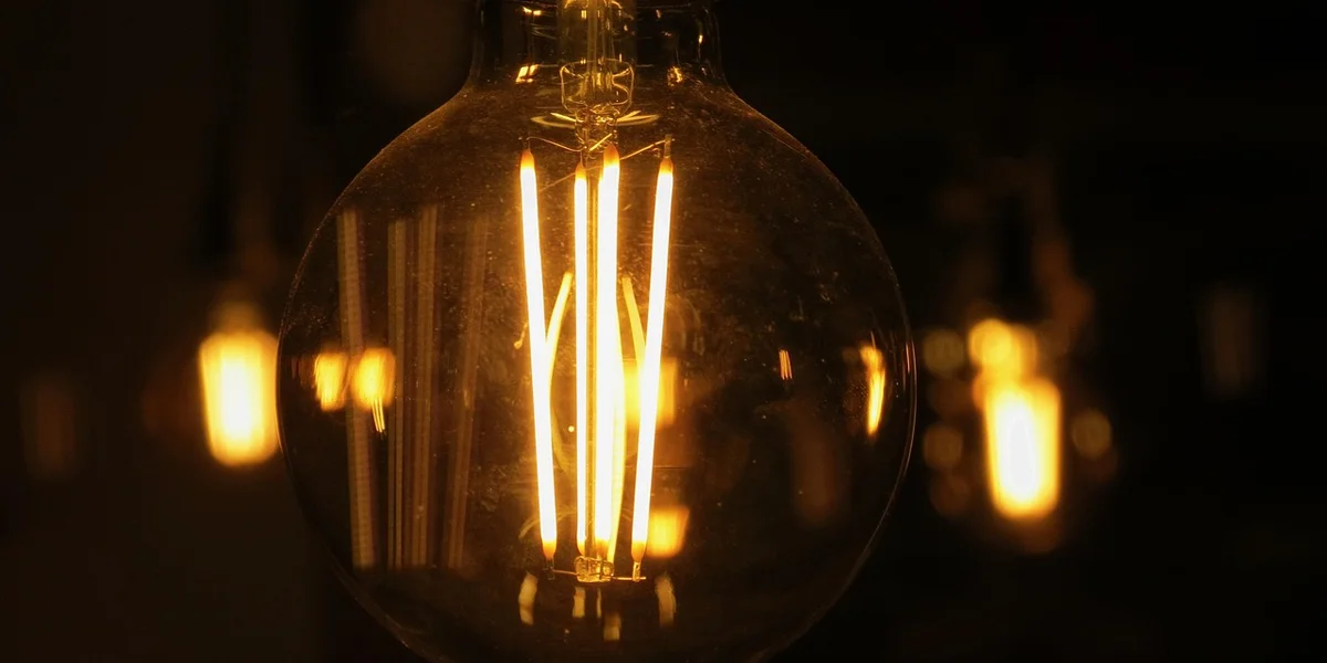 Close-up of a glowing incandescent heat lamp bulb with visible filaments.