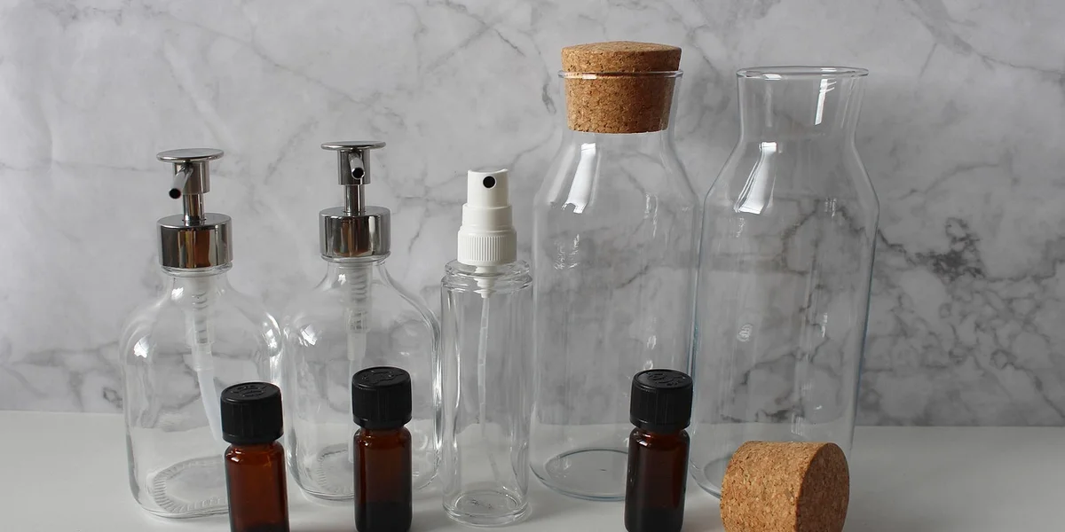 Assorted glass and amber misting bottles and jars arranged on a marble surface, illustrating gear used for misting leopard geckos and crested geckos.