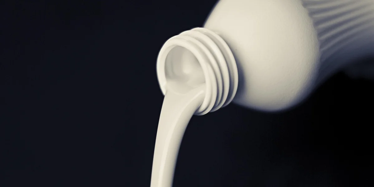 Close-up of a white squeeze bottle dispensing calcium powder.