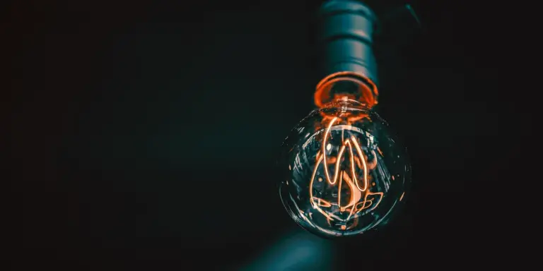 Close-up of a glowing vintage-style filament light bulb in a dark background