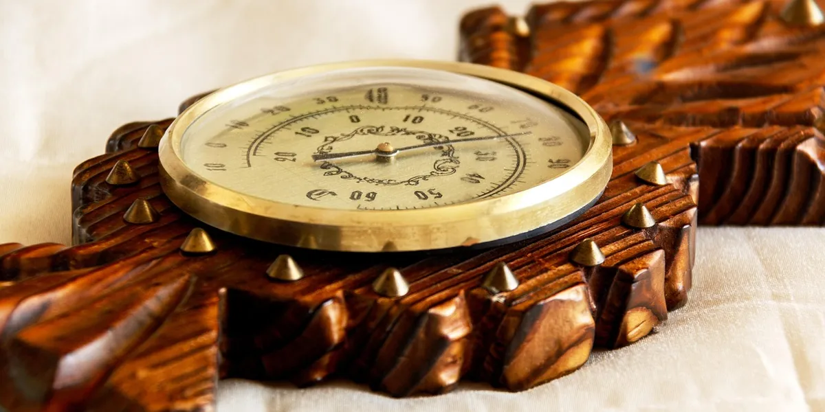 Analog dial thermometer resting on a carved wooden surface