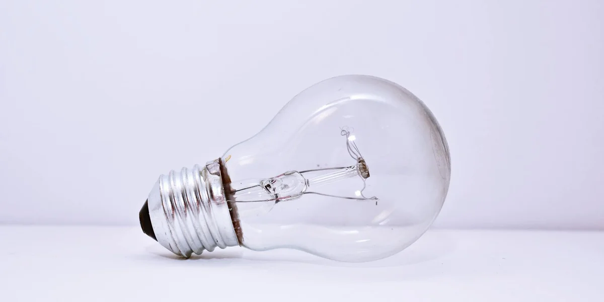 A clear glass light bulb lying on a white surface