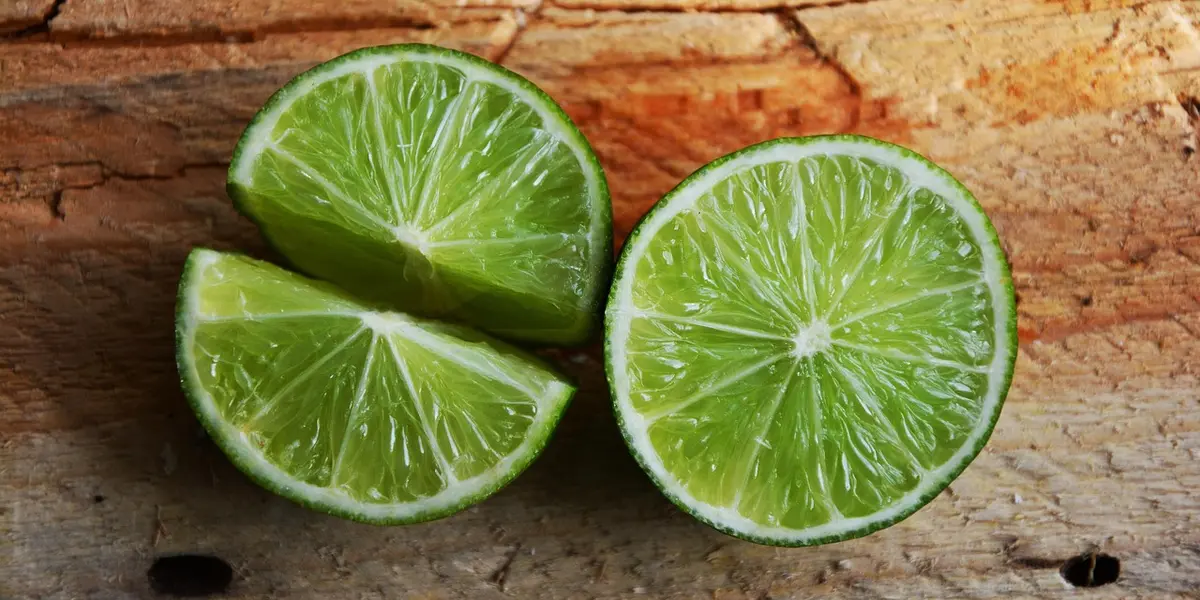 Two lime halves resting on a rustic wooden surface.