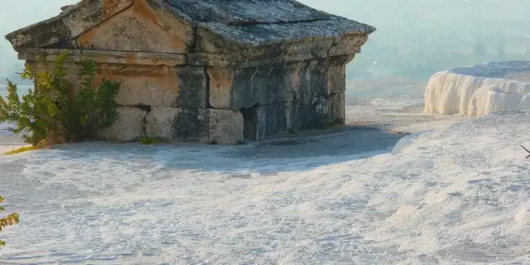 Stone shelter on bright white desert-like rock with a hazy horizon in the background.