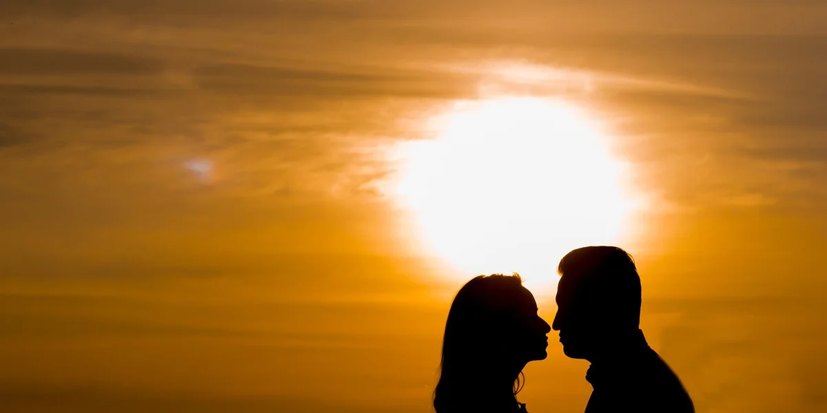 Silhouette of a couple kissing against a golden sunset