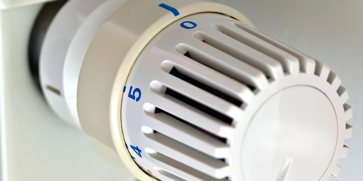 Close-up of a thermostat dial with temperature markings being adjusted