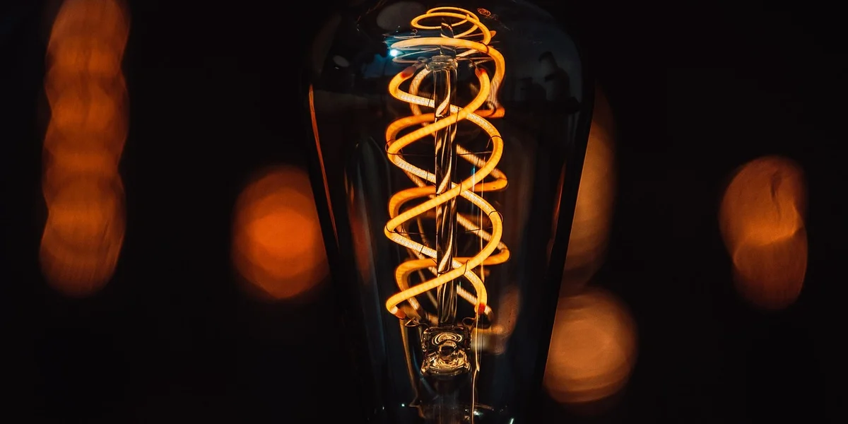 Close-up of a glowing spiral filament bulb with a warm orange glow and a blurred background
